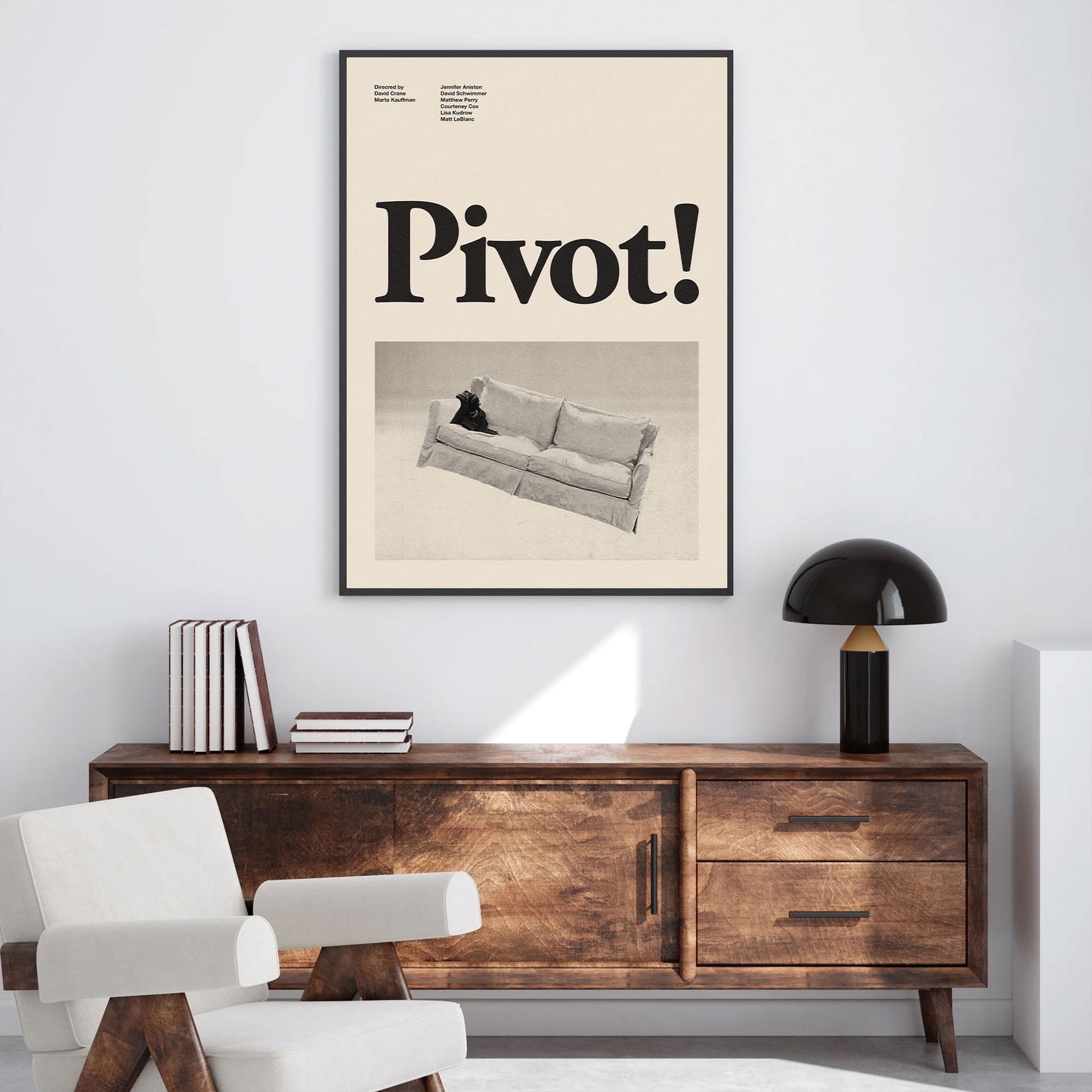 A minimalist mid century modern art print featuring the word "pivot" from the television series friends in black and white hanging in the living room filled with midcentury modern funiture